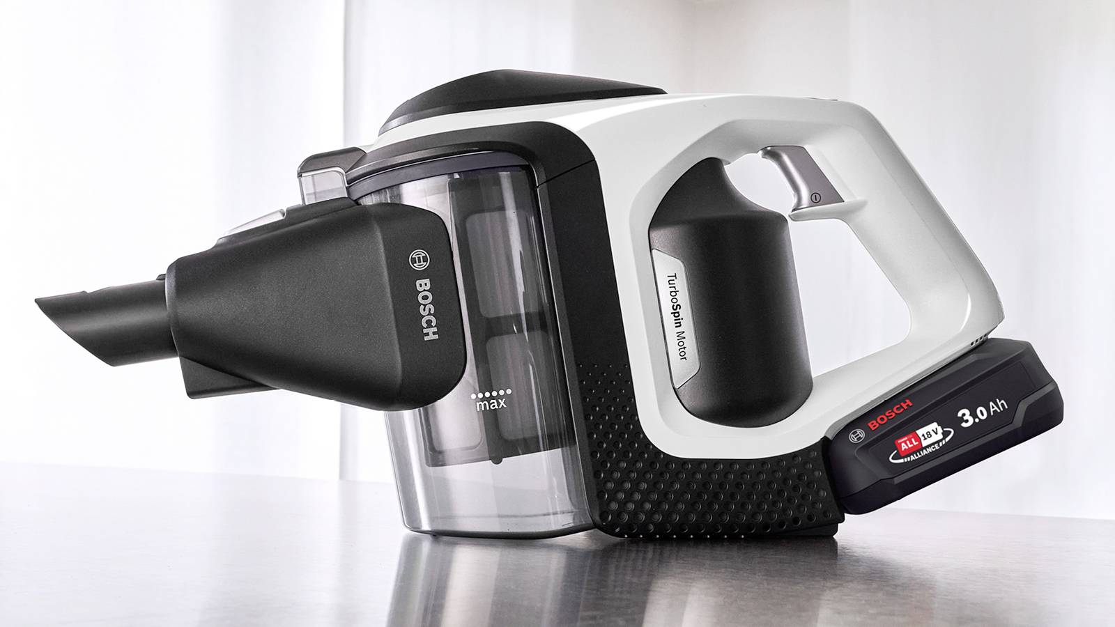 A Bosch handheld vacuum cleaner in a sleek design with a visible dust container and a detachable battery pack, resting on a table.