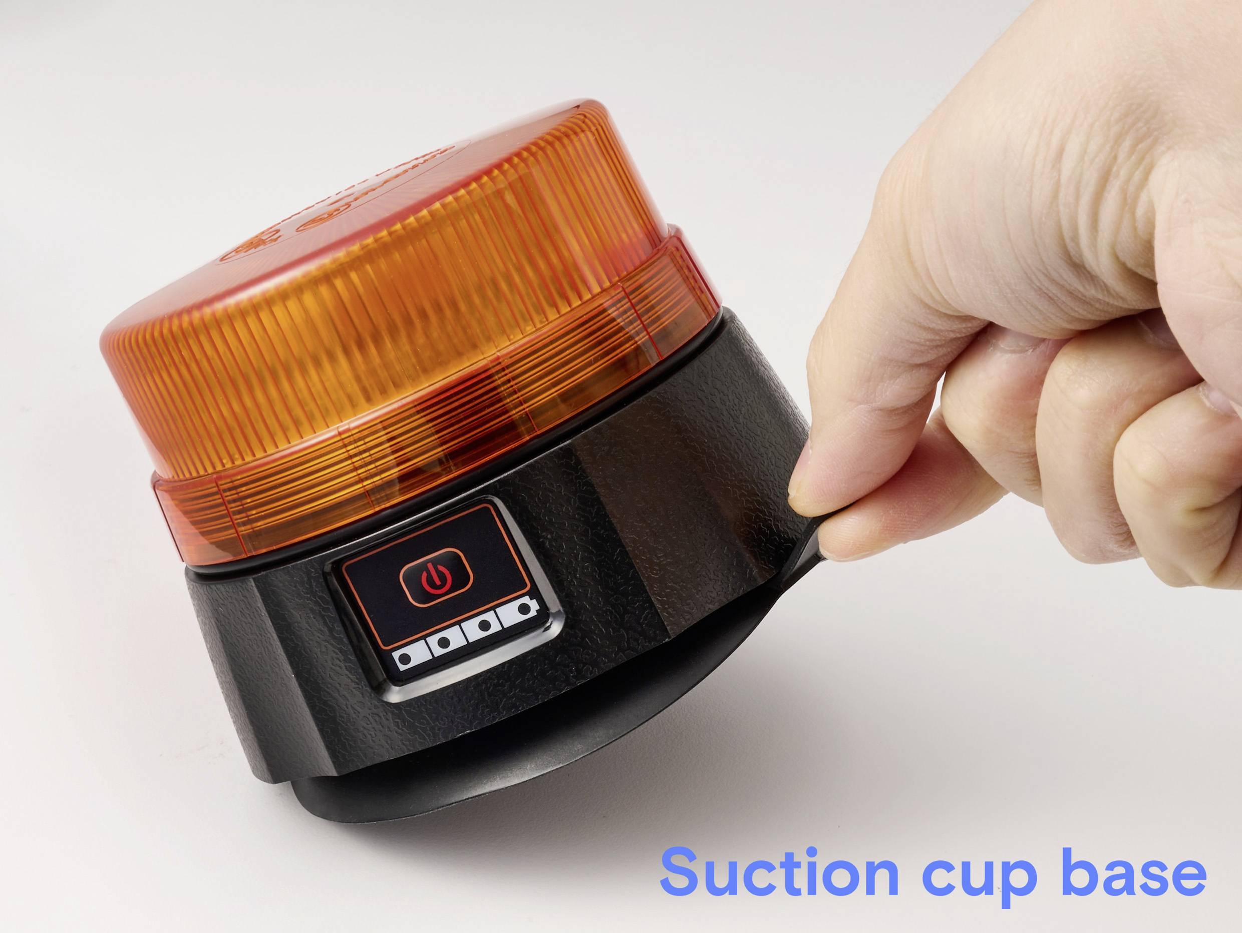 A hand pulling a suction cup base of an orange emergency light. The light features an on/off button on a black casing.
