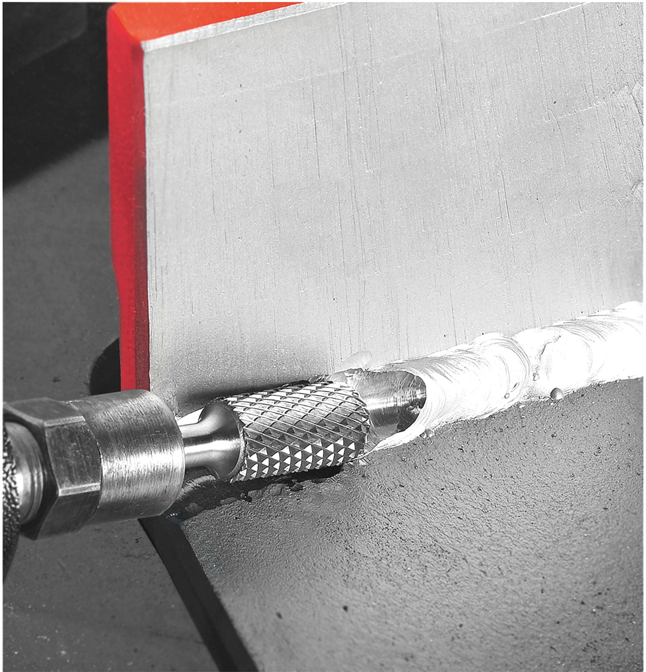 A tool is smoothing a welded seam on a metal surface, showing the process of finishing and polishing the weld for a refined appearance.