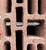A drill bit penetrating a red perforated brick at an angle, showing its ability to create precise holes in construction materials.