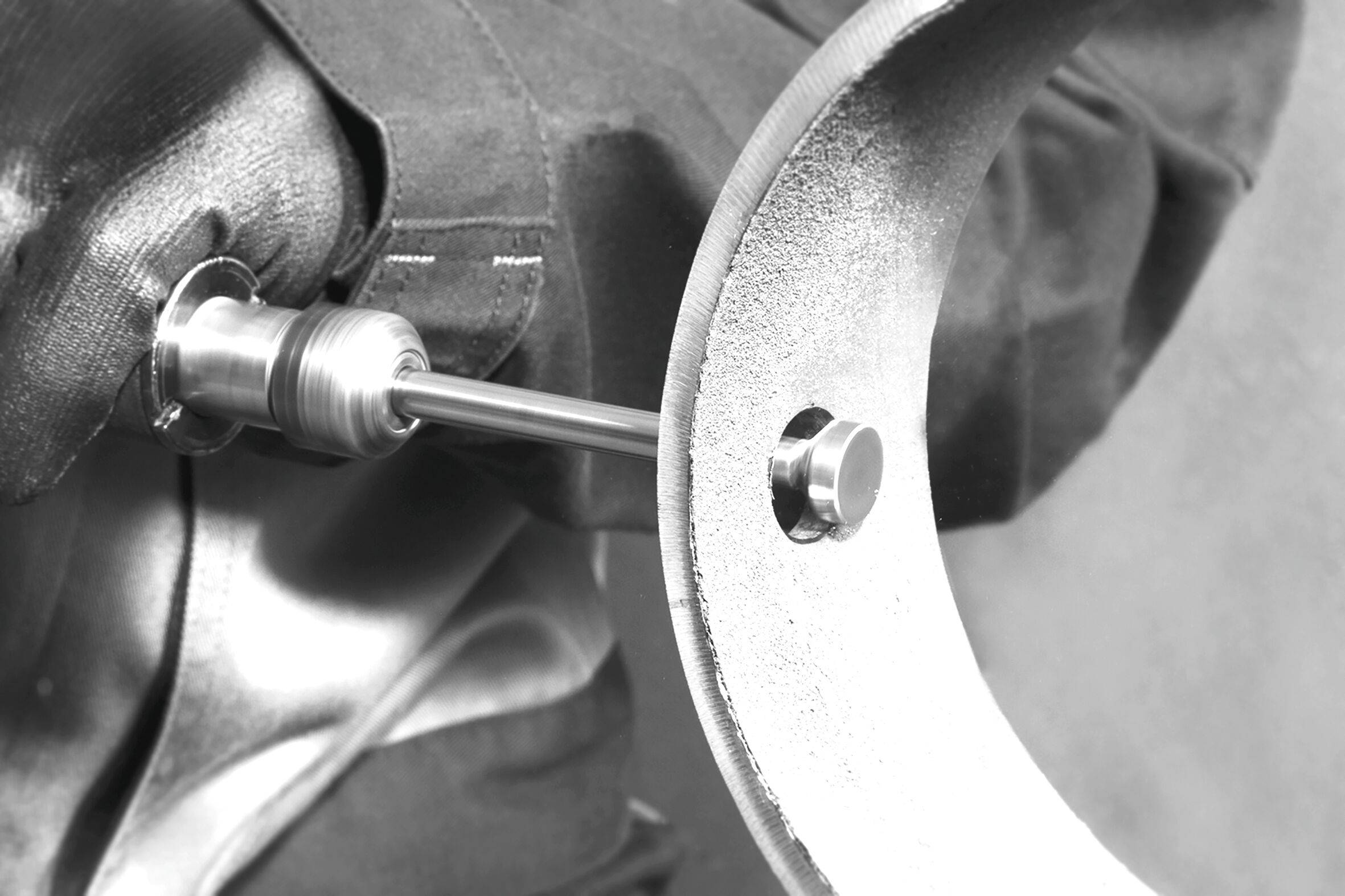 A close-up of a metalworking machine with a rotating tool engaged with a large curved metallic surface, indicating industrial fabrication.