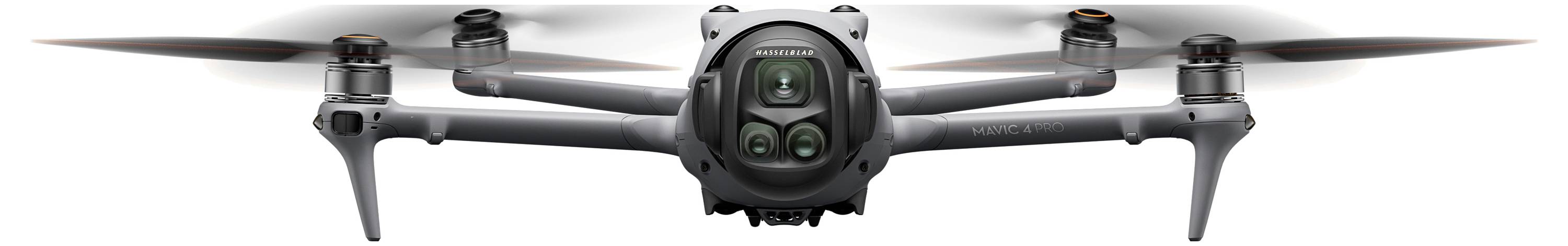 A quadcopter drone with four propellers and a camera is flying, facing forward, showing its compact and symmetrical design.