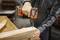 A person uses an electric drill to screw two wooden boards together on a workbench, highlighting woodworking construction.