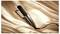 A black hair straightener rests on a smooth, silky fabric background. The brand name is visible on the straightener.