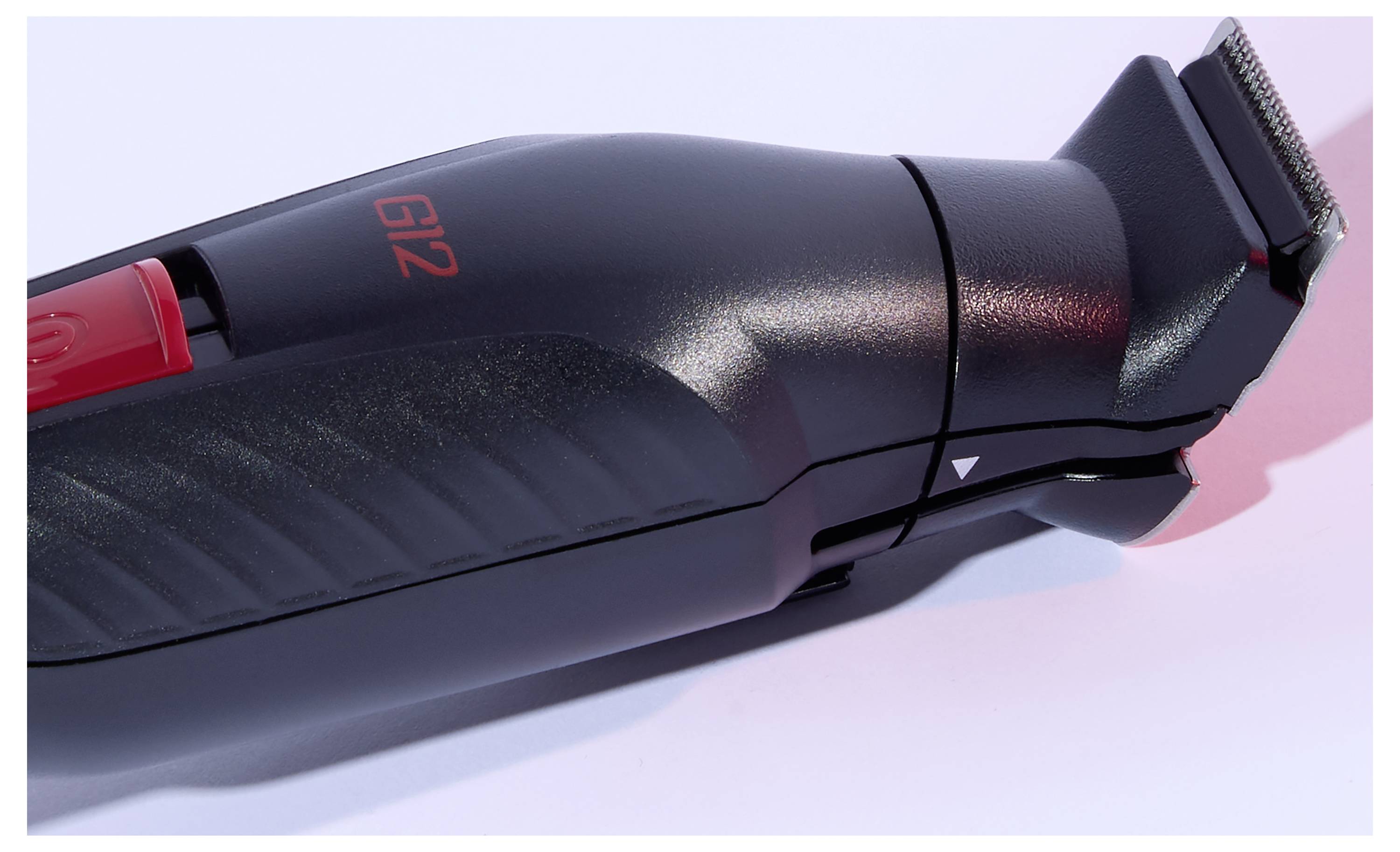 A black electric hair trimmer with red details, labeled 'G12', shown on a white surface.