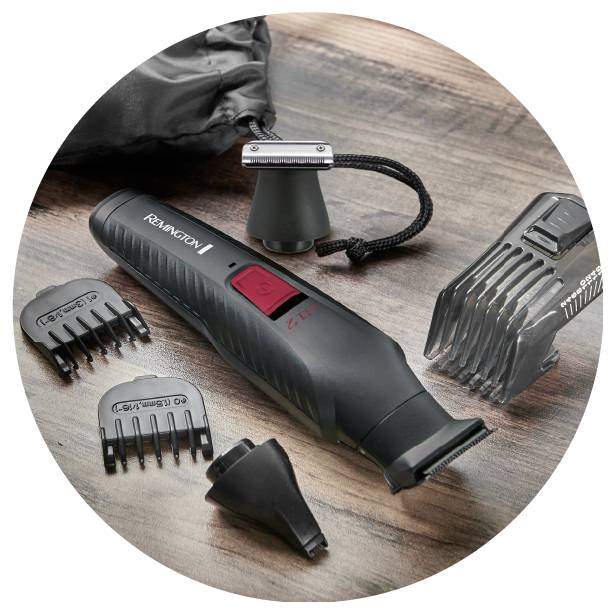 A grooming kit with an electric trimmer, adjustable comb attachments, a cleaning brush, and a small fabric case arranged on a wooden surface.