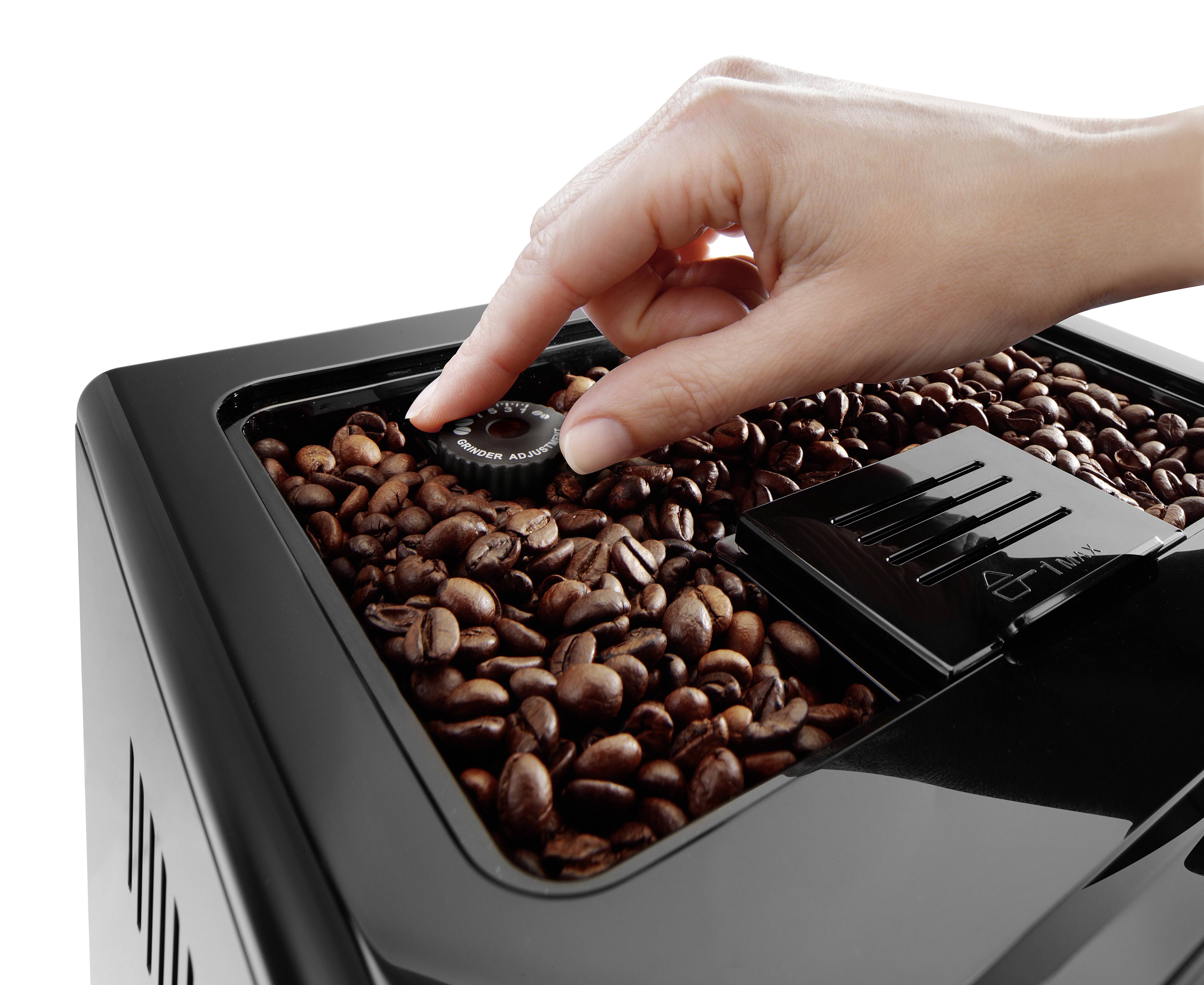 A hand adjusts a knob on a coffee grinder filled with whole coffee beans, indicating the machine's grind size setting function.