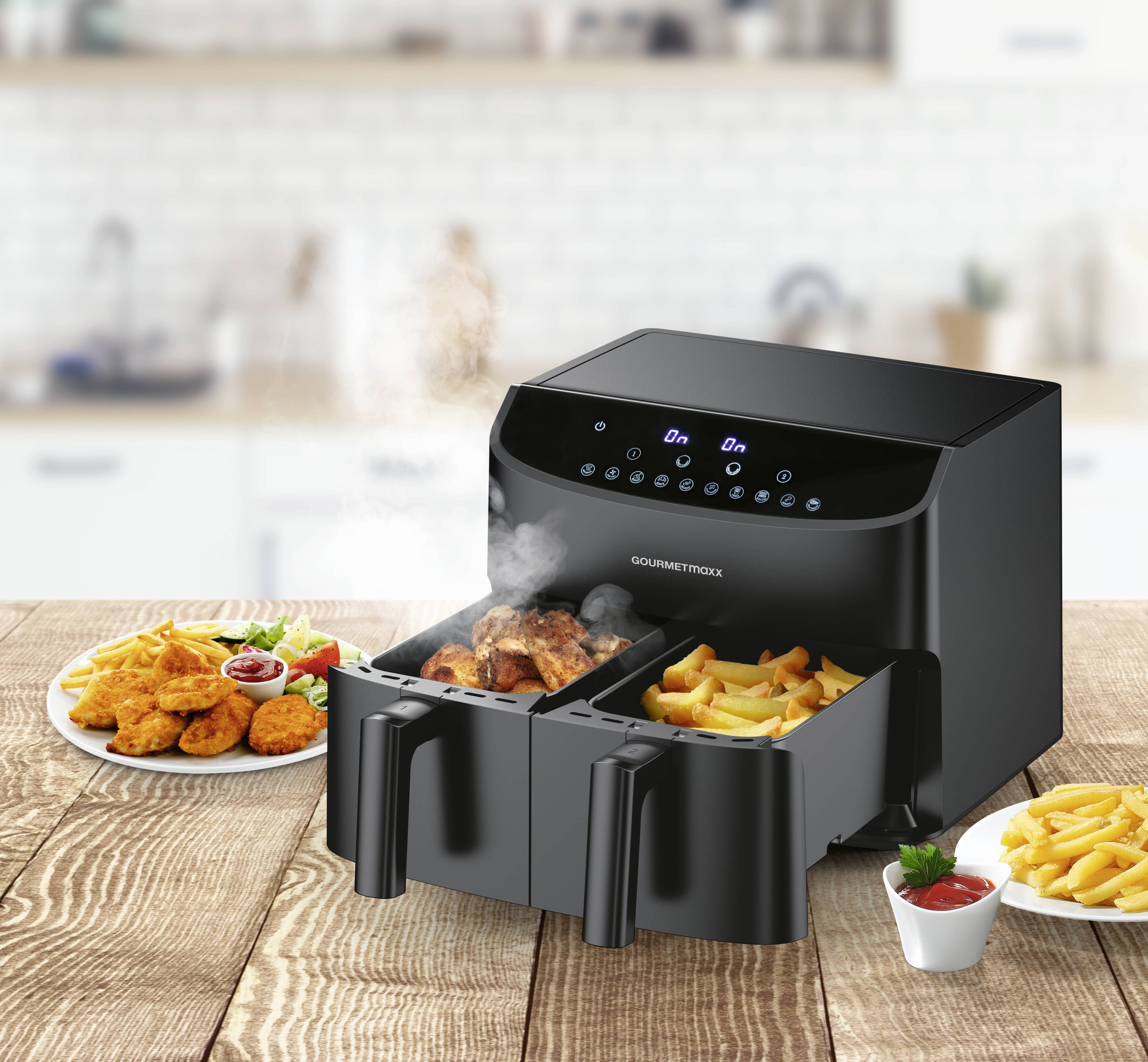 A double-basket air fryer on a kitchen counter cooking fries and chicken, with plates of food and sauce cups nearby.