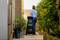 A person in a garden pushes a Bosch garden shredder along a paved path, surrounded by plants and greenery.