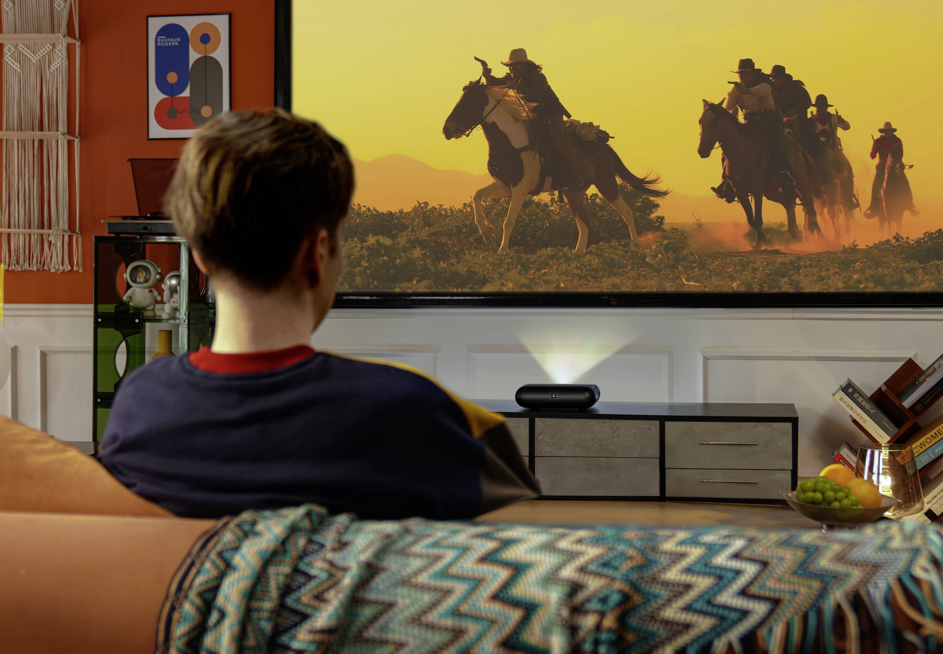 A person is watching a Western movie with riders on horseback on a large screen in a cozy, decorated living room.