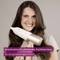 A person smiles while holding a hairdryer with the text 'Ionenfunktion für glänzendes, frizzfreies Haar, für ein geschmeidiges Finish'.