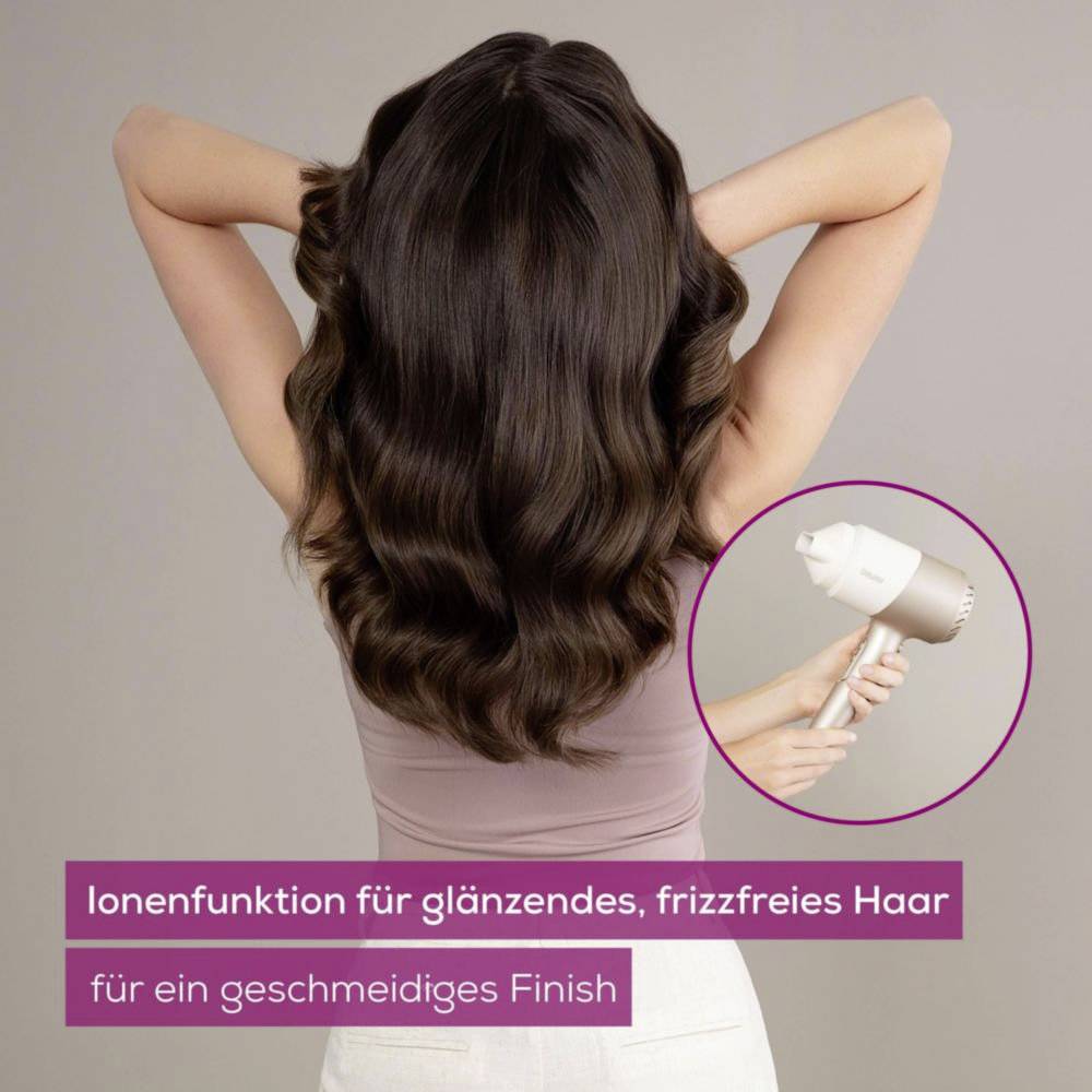 A person with long, wavy brown hair has their back to the camera, hands in their hair. Inset image shows a hair dryer. Text: 'Ionenfunktion für glänzendes, frizzfreies Haar für ein geschmeidiges Finish'.