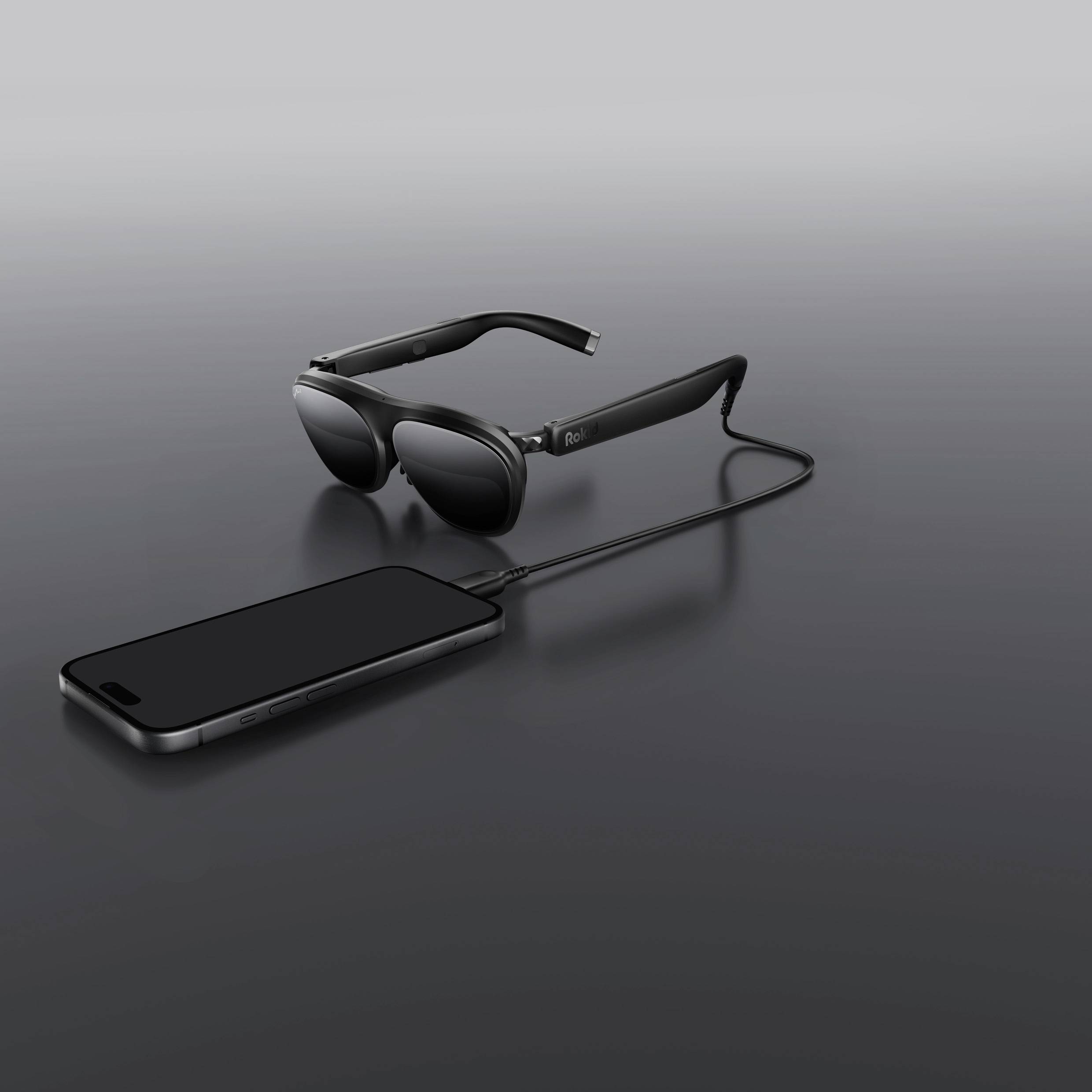 Virtual reality headset connected to a smartphone via a cable on a gray background.