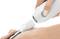 A person uses a handheld device to perform a skin treatment on the back of their hand, indicating a beauty or medical procedure.