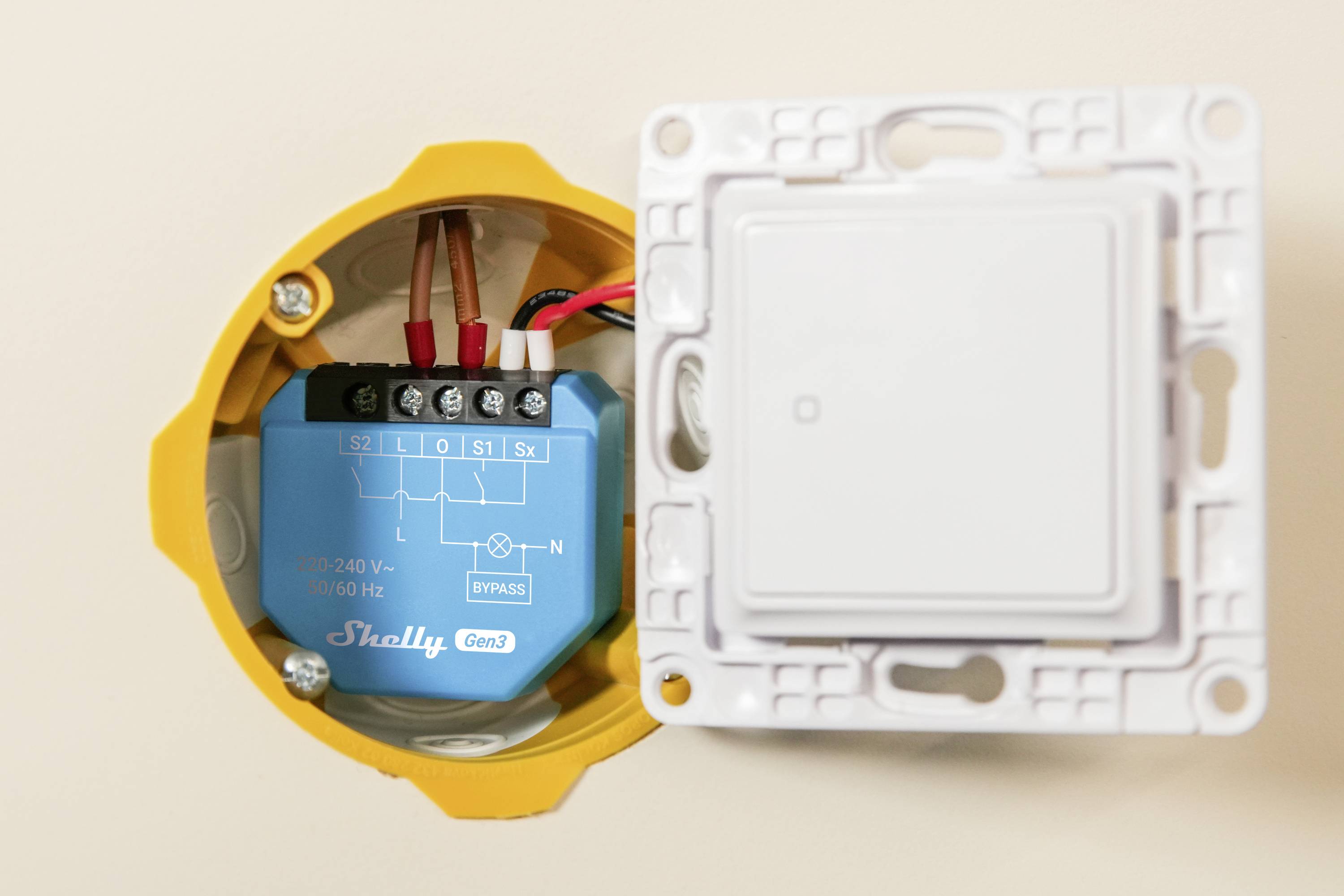 'Smart switch mechanism inside wall socket, showing wiring connections, labeled with voltage and brand.'