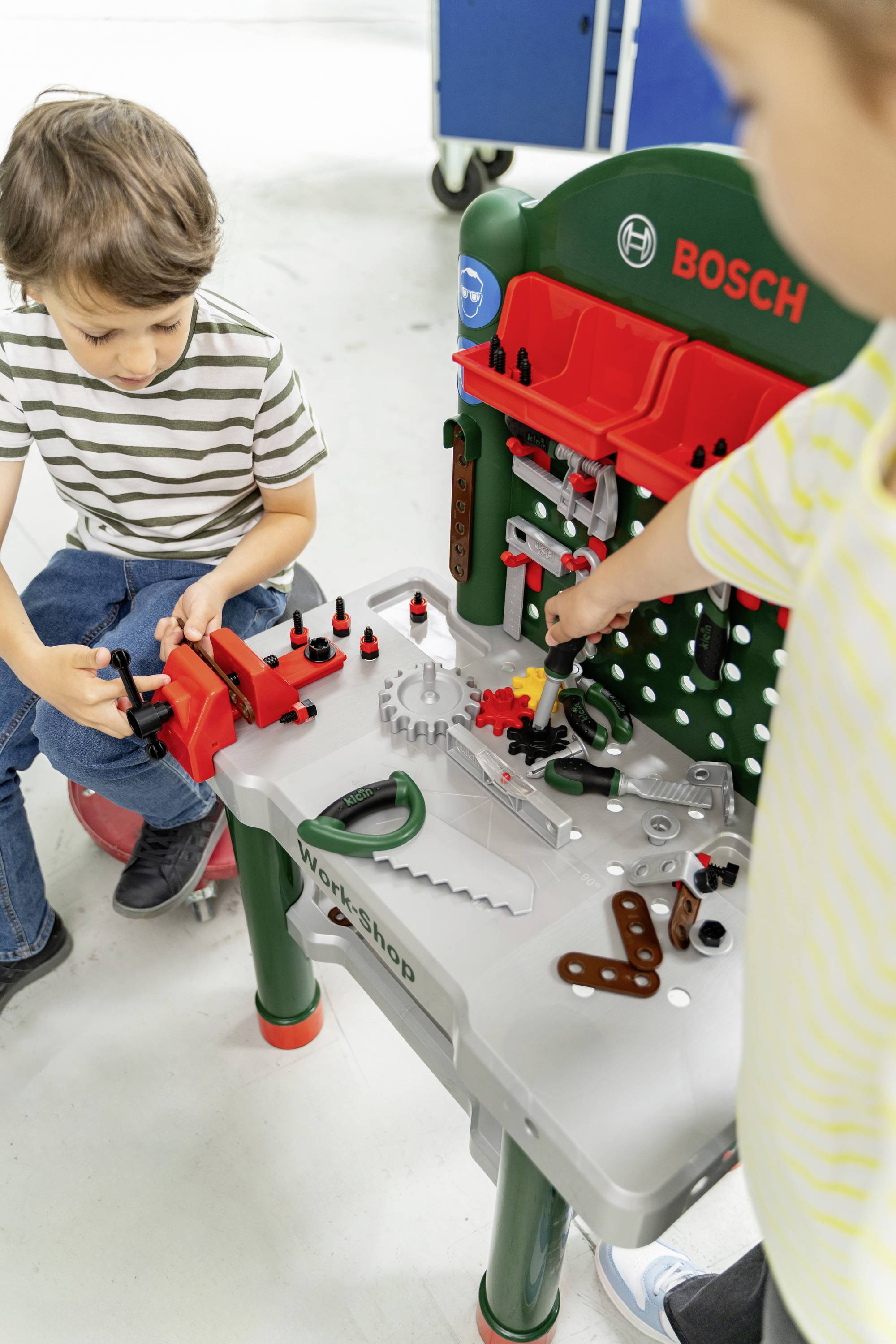 Children playing with a toy workbench, complete with tools and accessories, fostering creativity and motor skills through imaginative play.