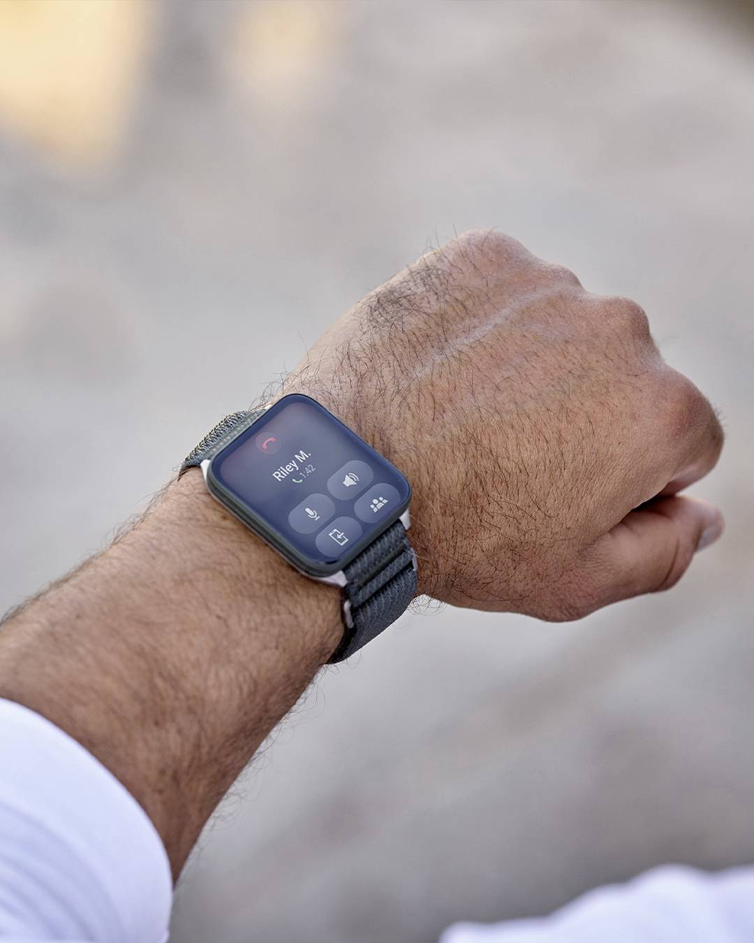 A person wearing a smartwatch displaying an incoming call with the options to answer or decline. The setting is outdoors.