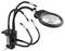 A magnifying glass with adjustable arms and clamps is attached to a desk, used for hands-free precision work.