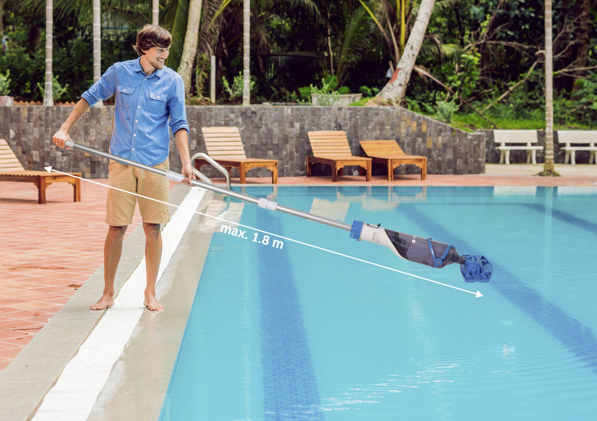 A person uses a pool cleaning net with an extendable handle beside a large swimming pool. Several lounge chairs are in the background.