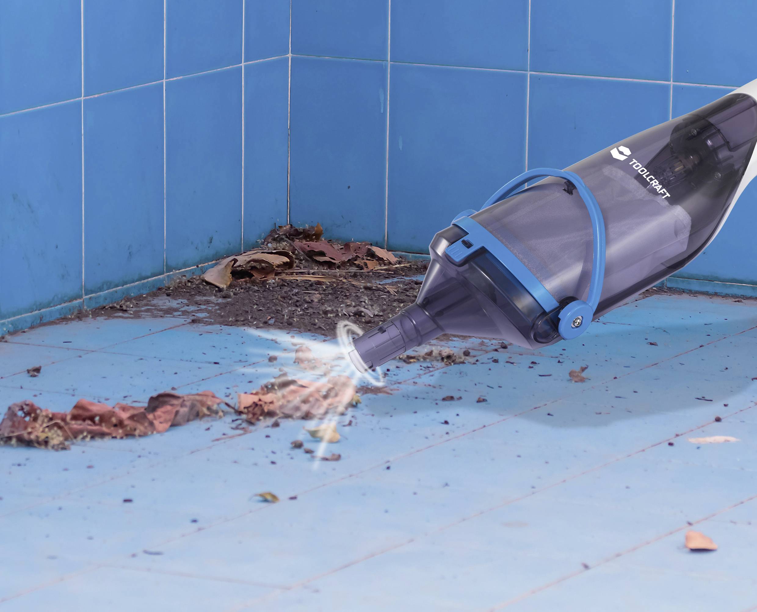 A handheld pool vacuum cleaning dirt and leaves from a blue-tiled surface at the corner of a pool, showcasing its suction power.