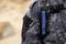A flashlight is clipped to the chest strap of a person wearing a tactical gray camo jacket, indicating readiness for outdoor activities.