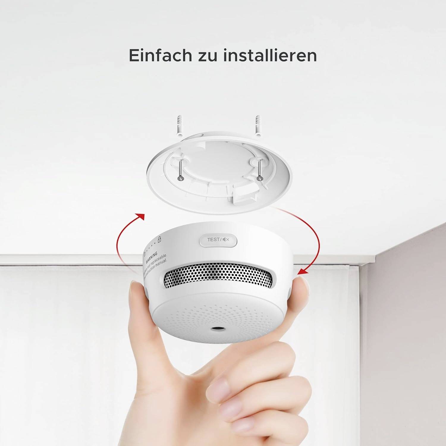 Smoke Detector Installation: A hand is holding a smoke detector pointing towards the ceiling. The smoke detector is open, ready for mounting.