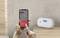 'A CO alarm triggered' message displayed on a phone held by a person, next to a digital carbon monoxide detector showing '999 ppm'.