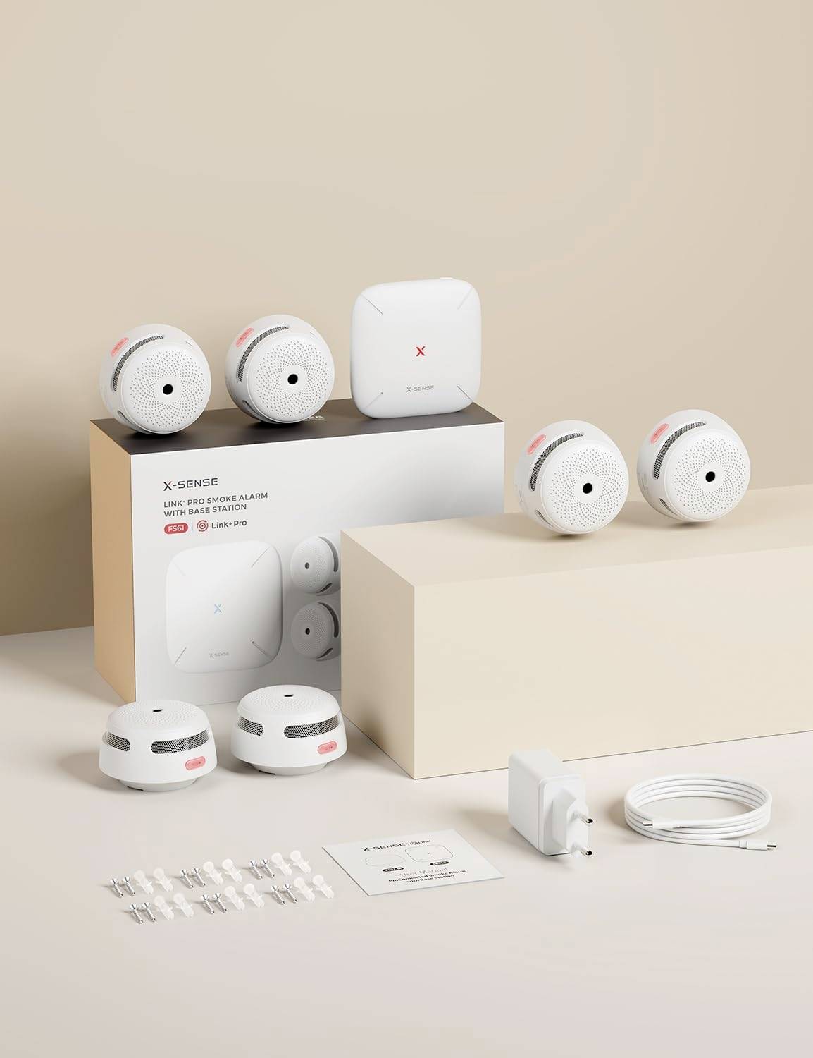 A set of six X-Sense smoke detectors with a central control unit, charger, cable, mounting hardware, and an instruction sheet on a beige background.