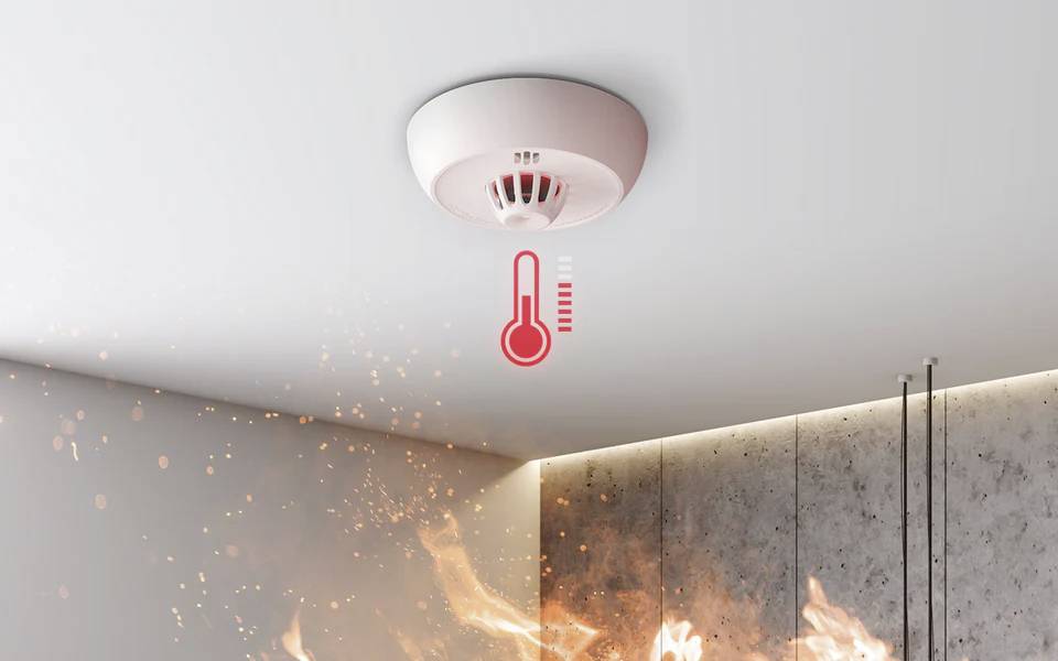 Smoke alarm on ceiling detecting fire with visible flames below; temperature icon indicates rising heat.