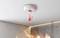 Smoke alarm on ceiling detecting fire with visible flames below; temperature icon indicates rising heat.