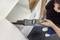 A person uses a vacuum cleaner with a narrow nozzle to clean inside a white cabinet, illustrating efficient dust removal.