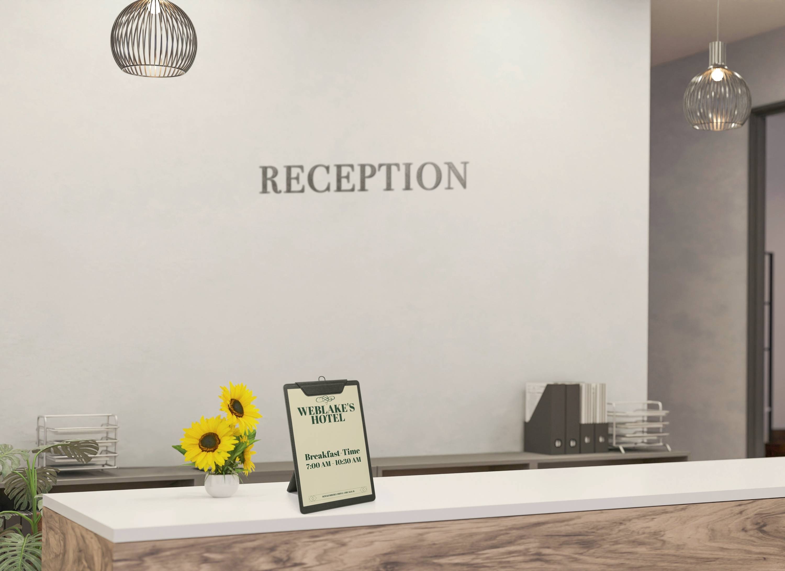 Reception desk with a sign listing breakfast hours, a bouquet of sunflowers, and a modern light fixture above.