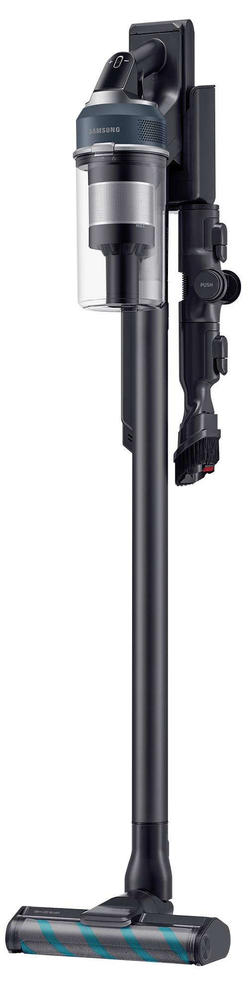A cordless stick vacuum cleaner in sleek gray, with a transparent dust container and multi-surface brush, is mounted on a wall charging station.