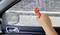 A hand uses a car window breaker to shatter a car's side window for emergency escape.