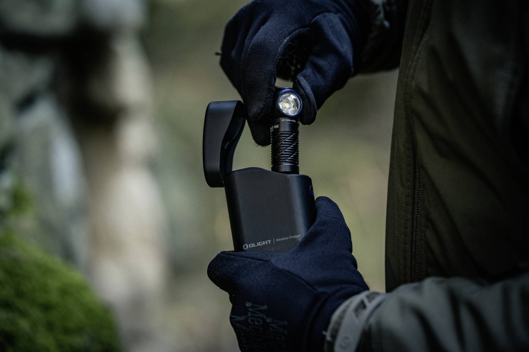 A person in gloves uses a black flashlight in a dimly lit outdoor setting. The flashlight is bright, highlighting its functionality.
