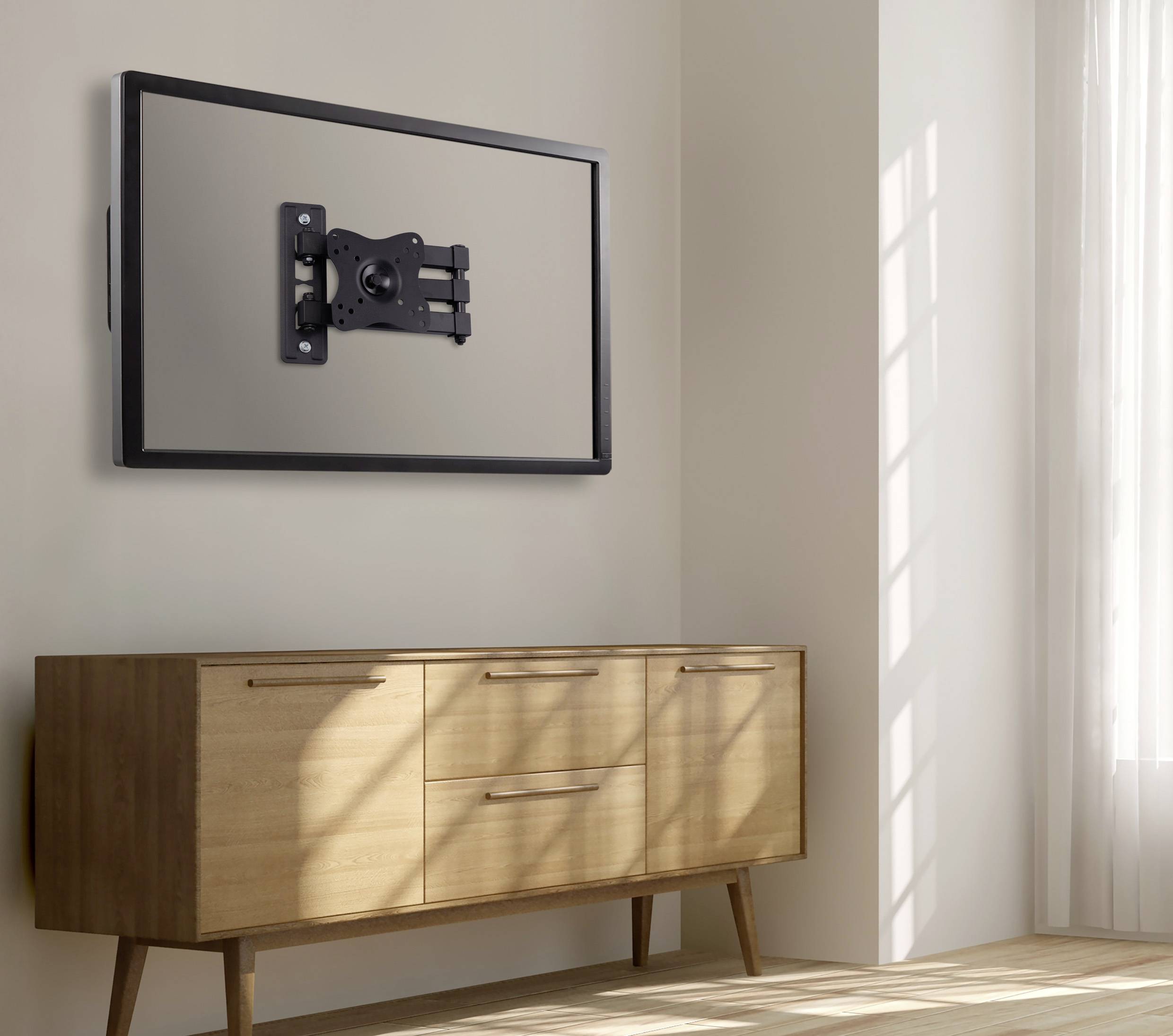 A wall-mounted TV with its screen removed, revealing the bracket, hangs above a wooden sideboard in a sunlit room.