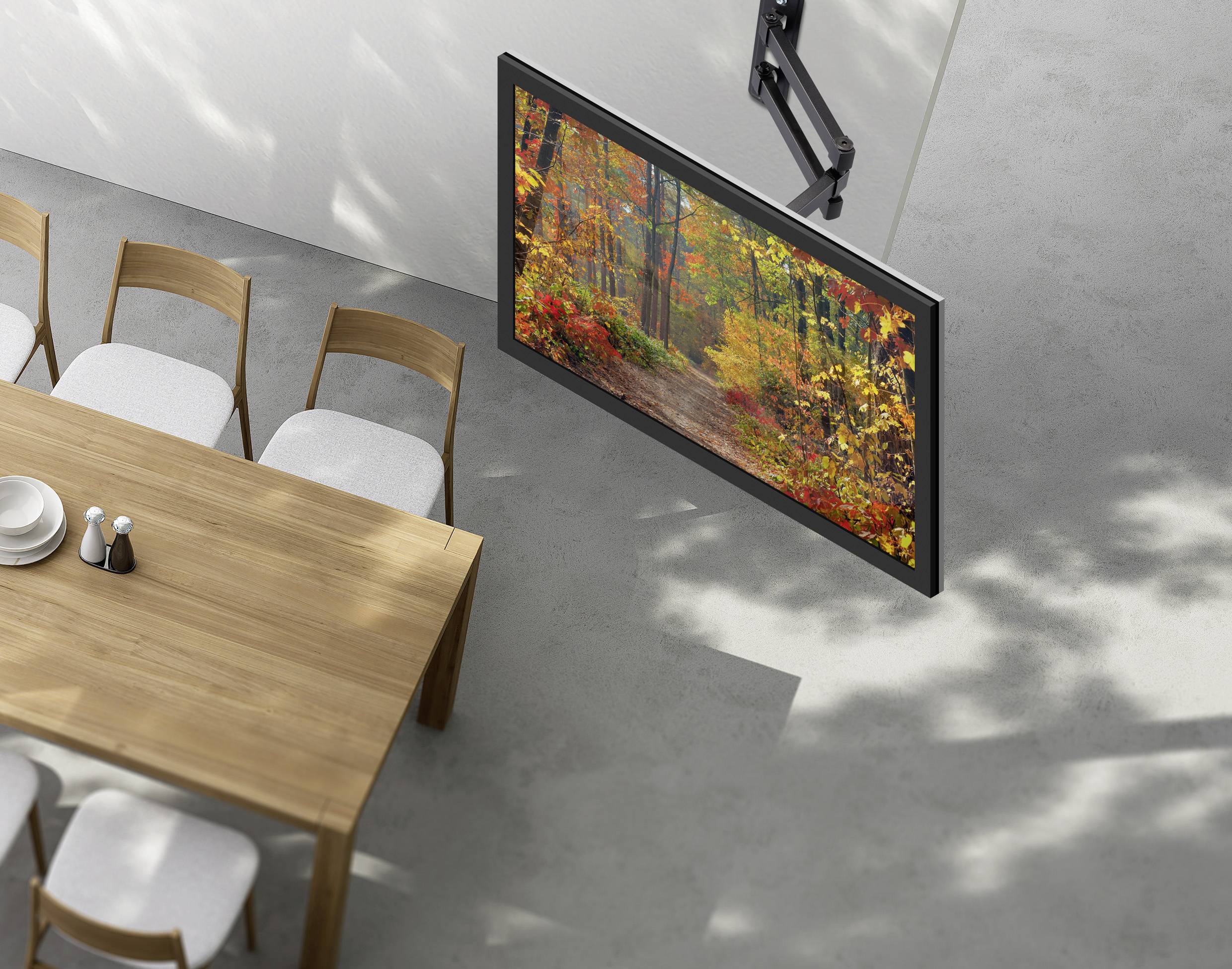 A wall-mounted TV displaying a colorful autumn forest scene is positioned next to a dining table with six chairs in a modern room.