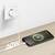 A smartphone on a wooden table is charging with a '60W' cable plugged into a wall socket, showing a charging symbol on the screen.