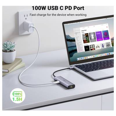 A laptop on a desk is connected to a power outlet via a USB-C hub. The screen displays music software. Text on image: '100W USB C PD Port'.