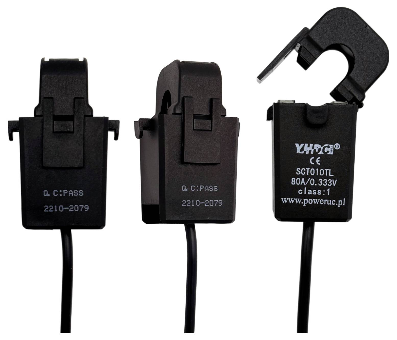 'Three black electrical current transformers with 'C:PAS' labeling; one is open showing its internal clamp mechanism.'