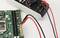 'A multimeter connected to a computer motherboard, measuring electrical parameters.'