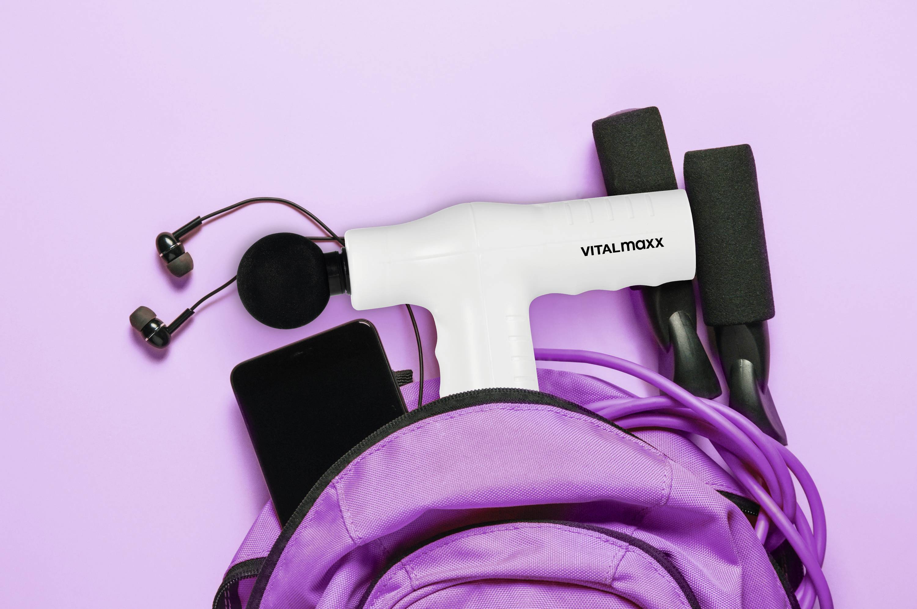 Massage gun, earphones, and jump rope in a purple backpack on a pink background, suggesting fitness or travel preparation.
