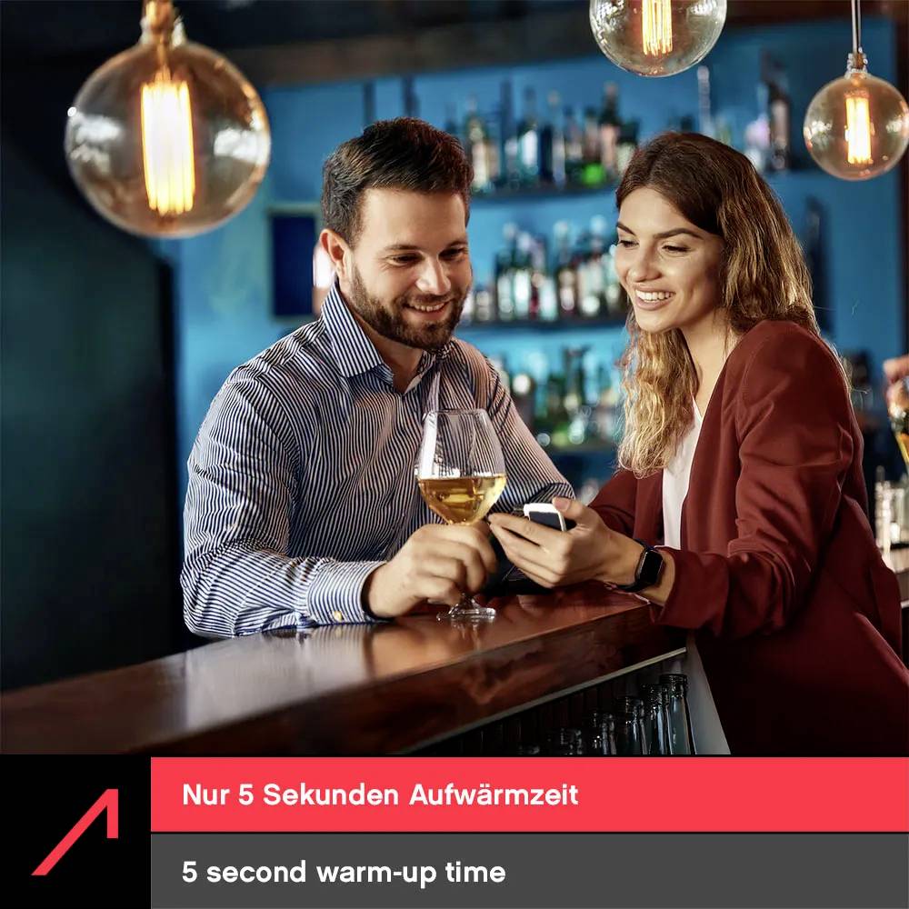 A man and woman at a bar, smiling and toasting with drinks. Text reads '5 second warm-up time' in English and German below.
