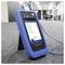 A blue network tester device with a display screen showing interface details, standing on a carpeted floor in an office setting.