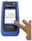 A blue handheld device displays a Wi-Fi channel graph. A finger touches the screen, indicating interaction with the SignalTEK QT model.