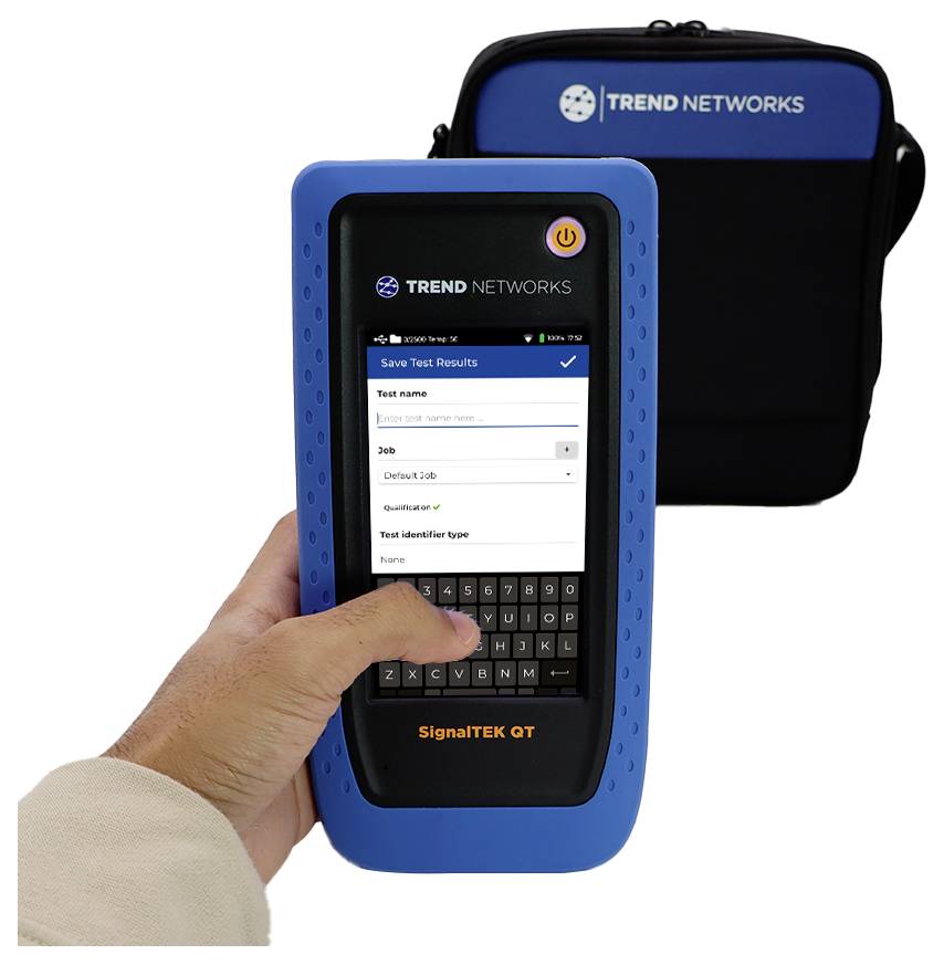A person holds a blue SignalTEK QT device displaying test results with a 'Job' field on screen; a Trend Networks bag is in the background.