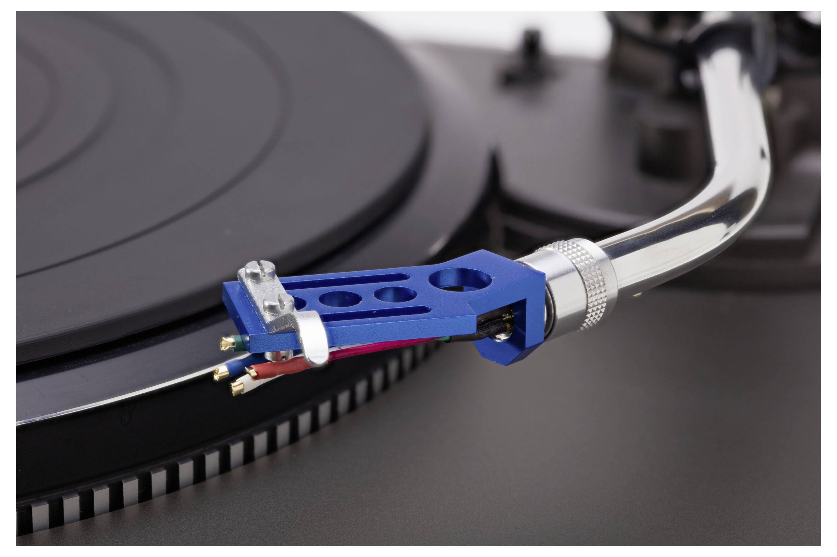 Close-up of a turntable's tonearm and stylus on a vinyl record, showcasing the intricate design and components of the record player.