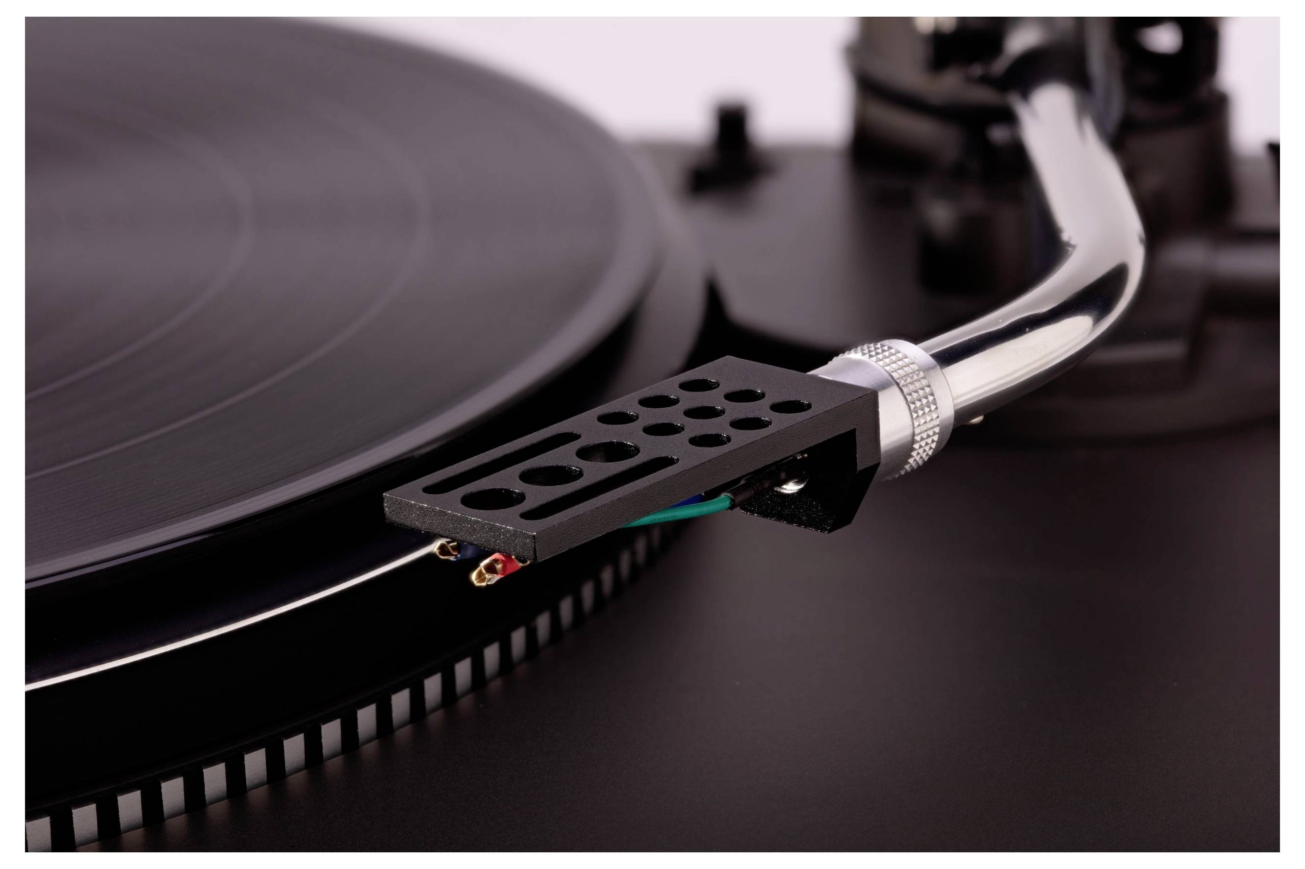 A close-up of a vinyl record spinning on a turntable, focusing on the tonearm and needle engaging with the record's grooves.