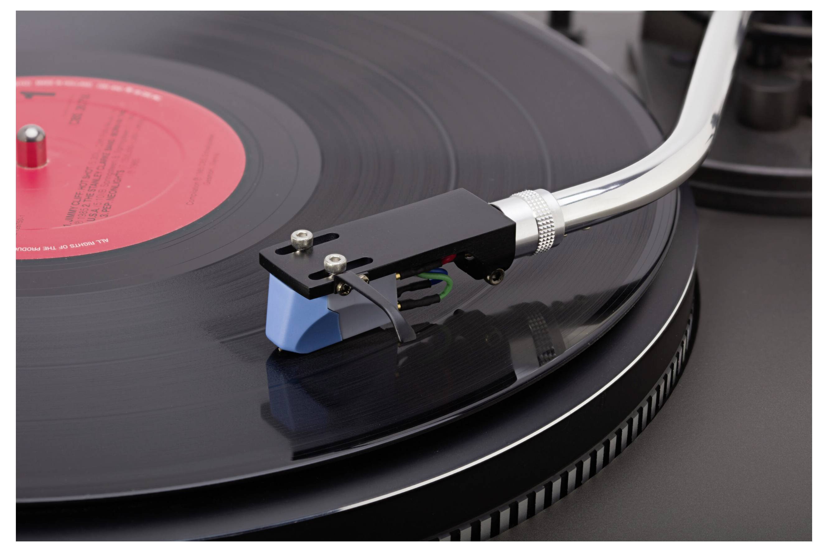 'A close-up of a turntable needle on a spinning vinyl record, highlighting the grooves and label.'