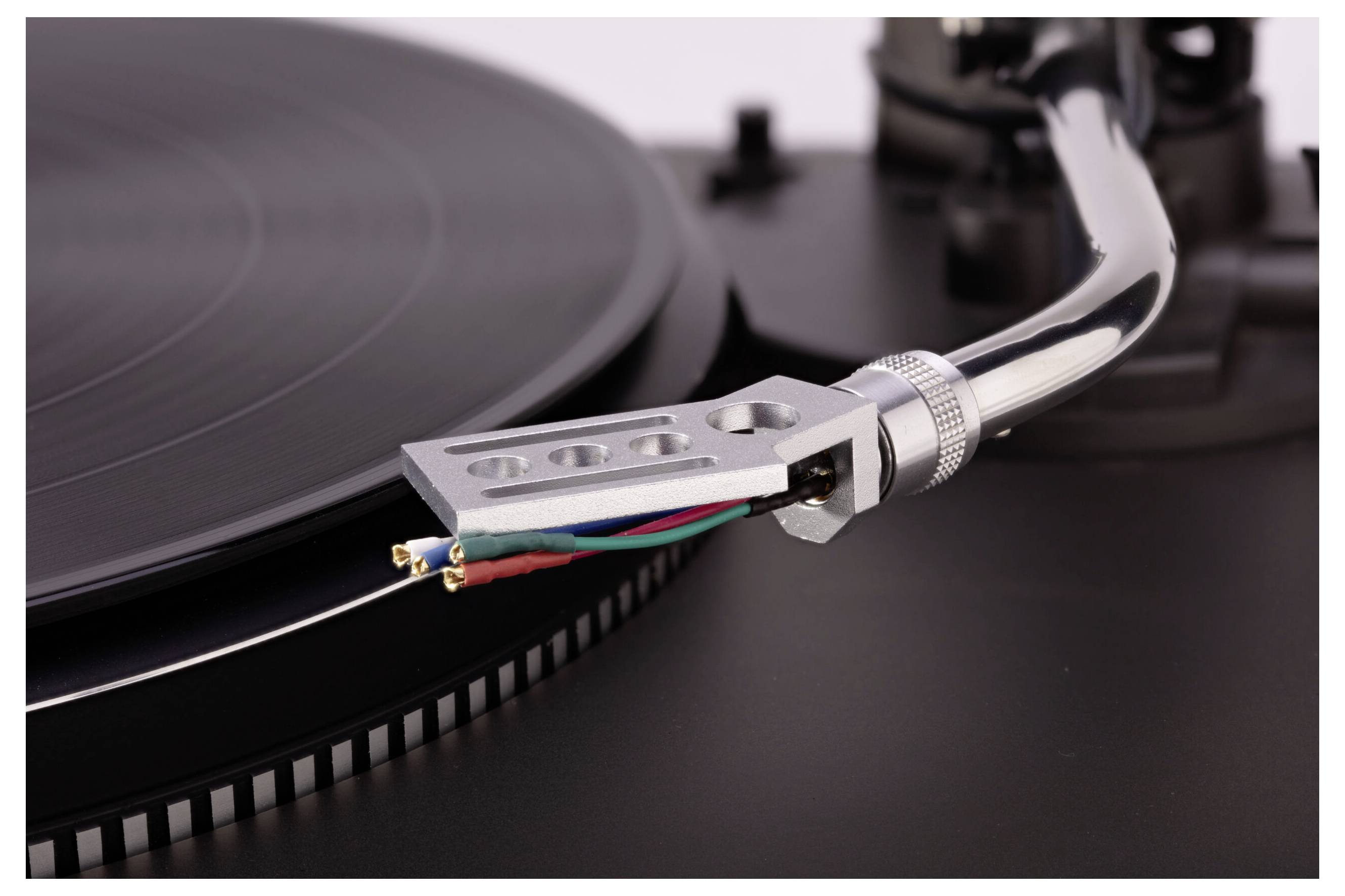A close-up of a turntable's tonearm and needle positioned over a spinning vinyl record, highlighting the precision and design elements.